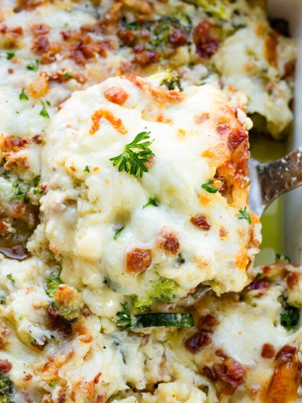 a photo of a serving of golden baked lasagna being lifted out of a pan full of lasagna
