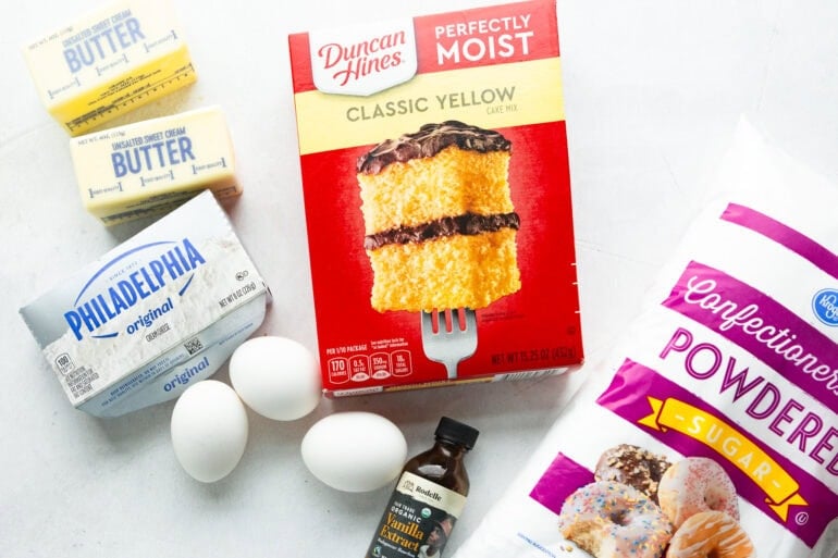 ingredients for paula deens ooey gooey butter cake including yellow cake mix, powdered sugar, cream cheese, butter, and eggs.