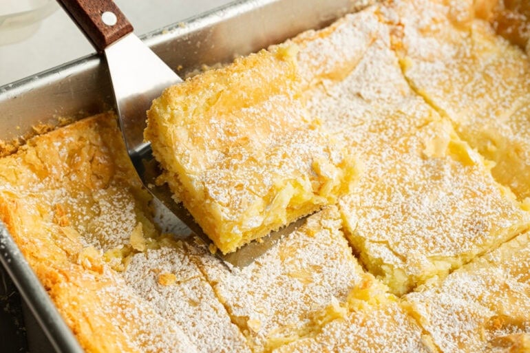 A spatula is taking a serving out of a 9x13 pan of butter cake