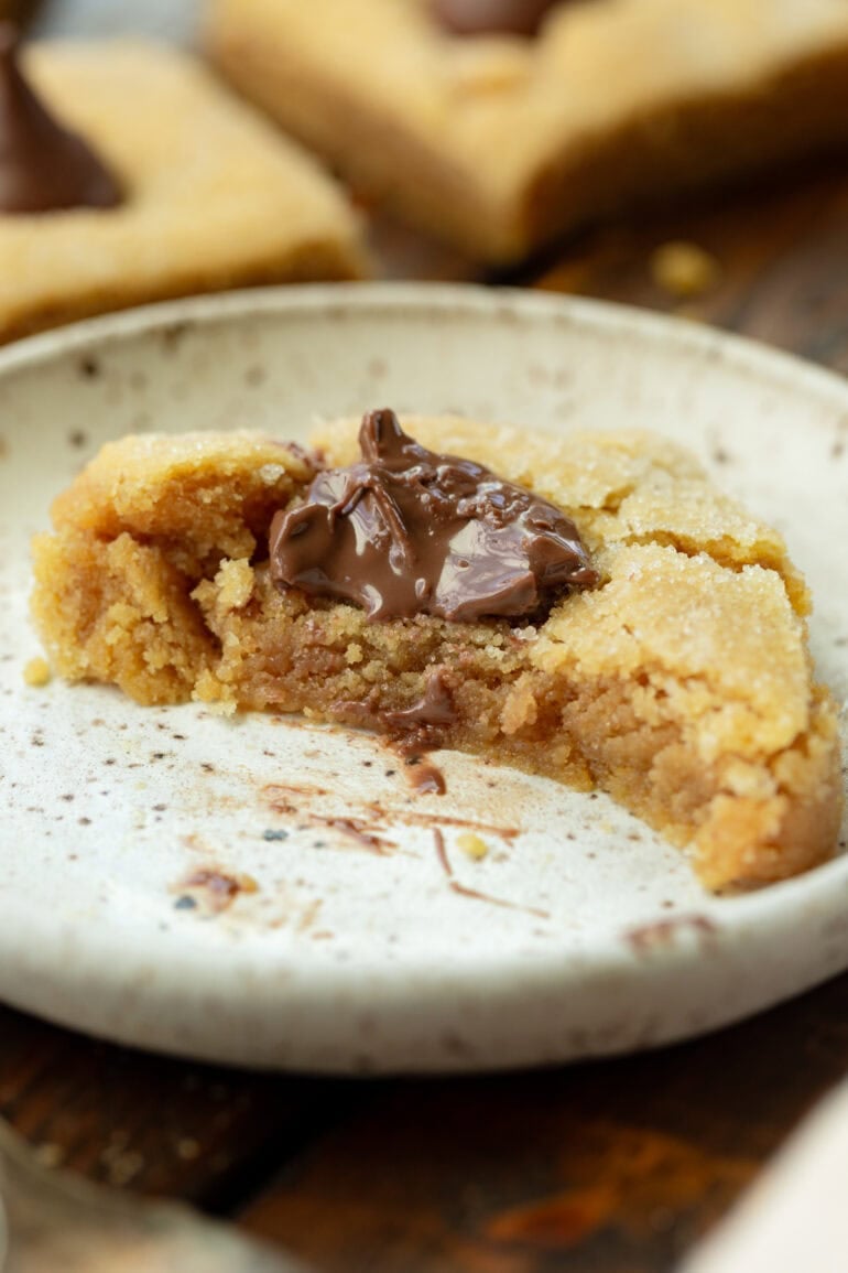 A peanut butter flower bar on a small plate with a large portion of the bar missing so you can see the cross section
