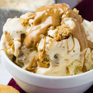 A photo of a bowl of homemade peanut butter cookie ice cream drizzled with creamy peanut butter one top and full of cookie chunks.