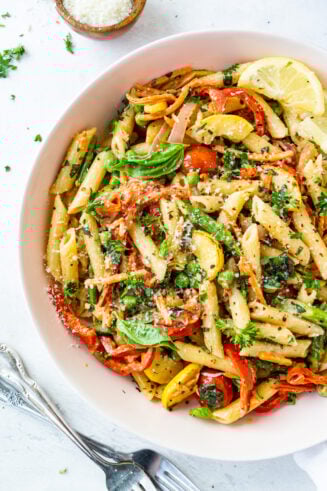 a photo of a large bowl full of penne pasta tossed with vegetables and a creamy sauce