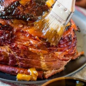 Brushing sauce on a Brown Sugar Ham.