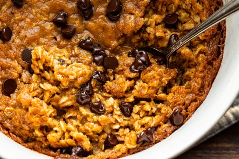 a pumpkin chocolate chip baked oatmeal with a spoon scooping up a serving