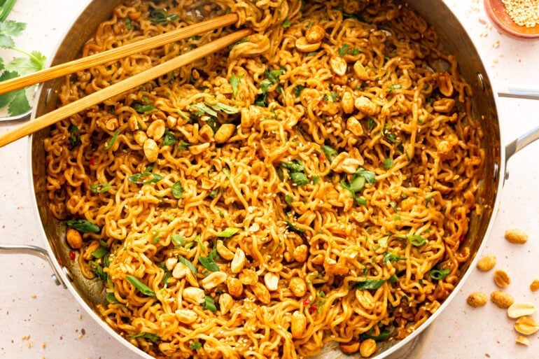 a large pan of peanut butter ramen sprinkled with peanuts, green onions and sesame seeds