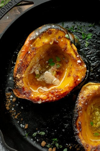 a photo of a halved acorn squash that has been roasted until golden and caramelized with brown sugar and butter