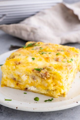 a photo of a piece of cheesy sausage breakfast souffle sitting on a small plate