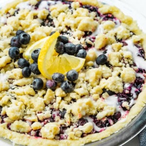 a photo of a whole baked wild blueberry pie in a shortbread crust with a streusel topping and a vanilla glaze.