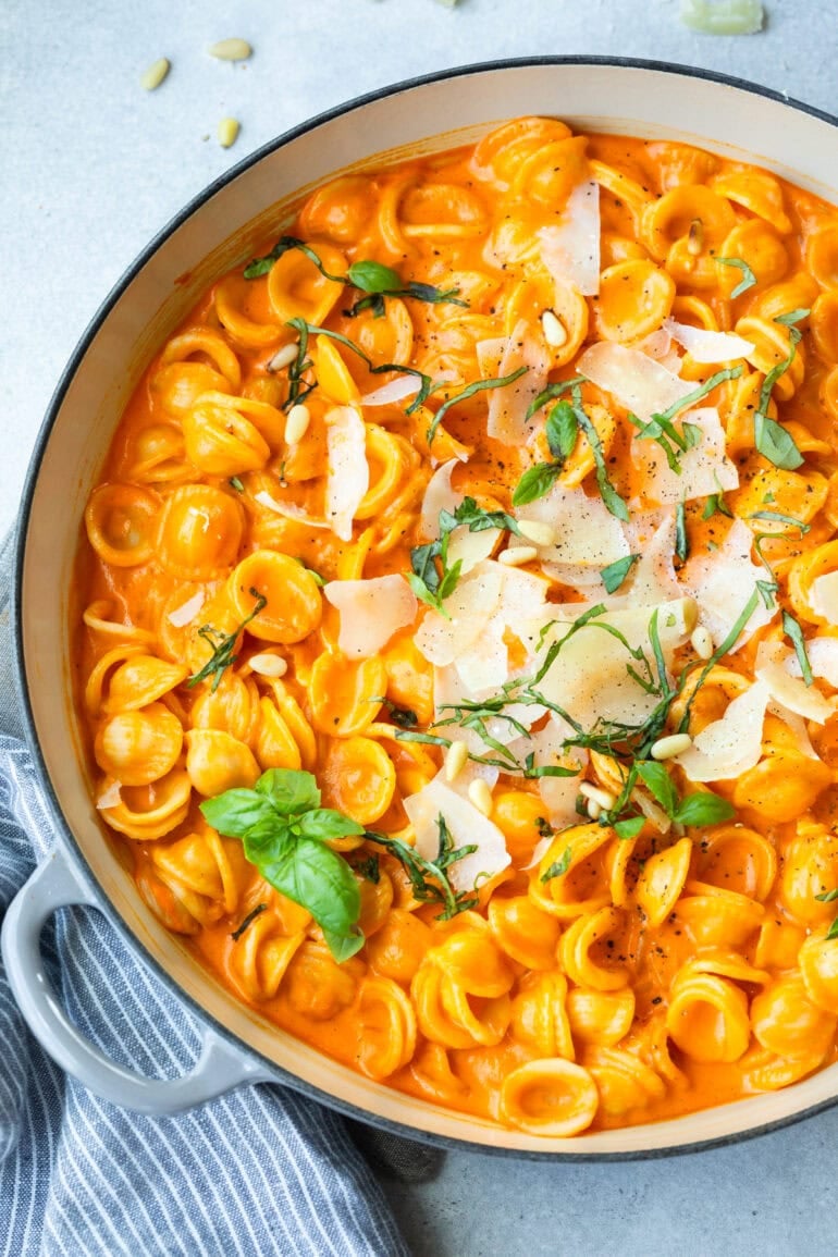 a large dutch oven full of cooked orecchiette pasta mixed with creamy roasted red pepper pasta 