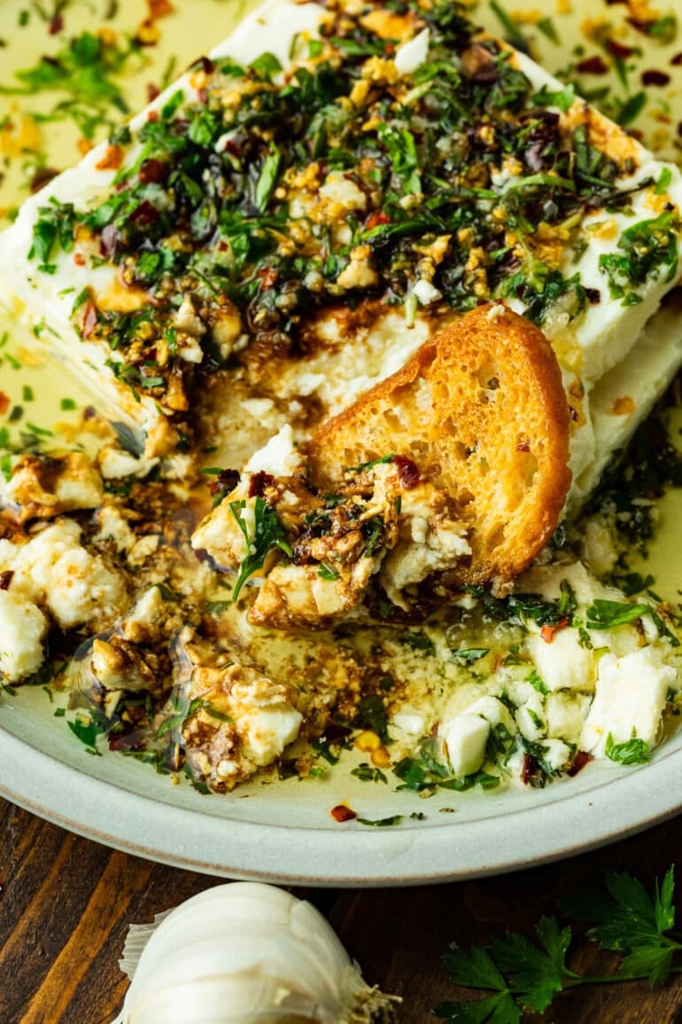 a crostini dipped into a creamy herb feta dip