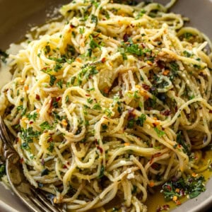a photo of hot sizzling italian oil over fresh spaghetti and loaded with fresh herbs