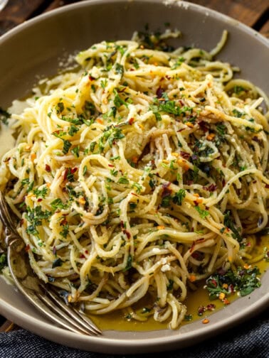 a photo of hot sizzling italian oil over fresh spaghetti and loaded with fresh herbs