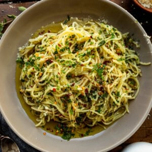 a photo of hot sizzling italian oil over fresh spaghetti and loaded with fresh herbs
