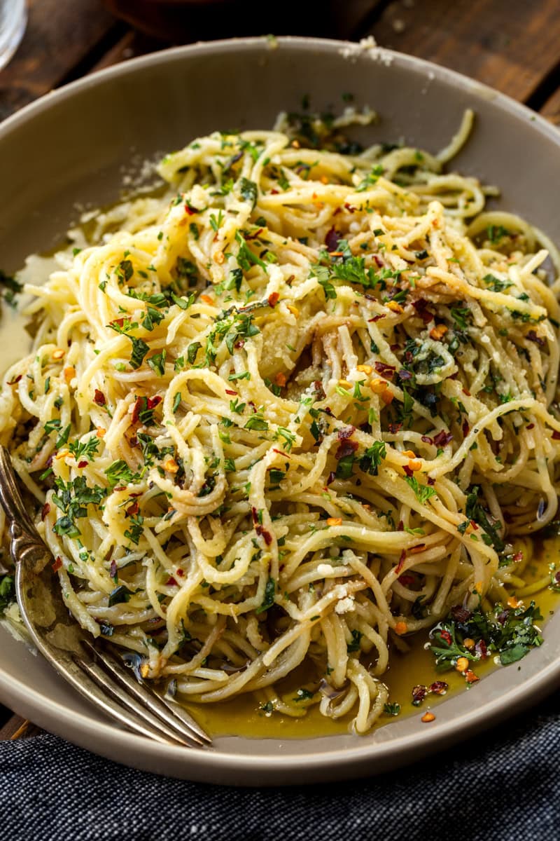 a photo of hot sizzling italian oil over fresh spaghetti and loaded with fresh herbs