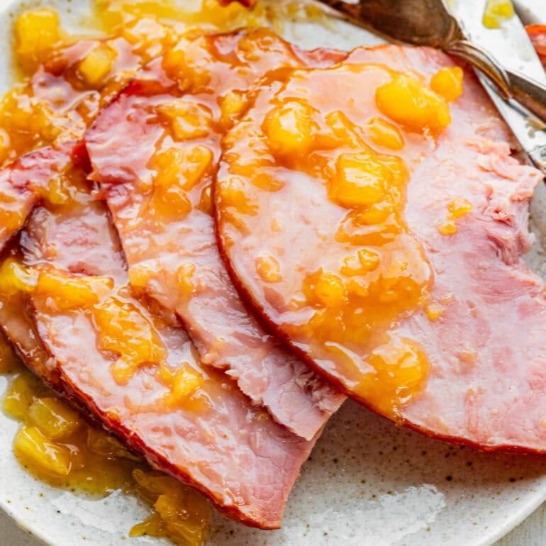 a photo of a spiral cut ham sitting on a serving platter topped with a juicy pineapple glaze