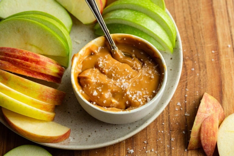 A plate of apples and a bowl of rich, velvety caramel sauce with flaky salt