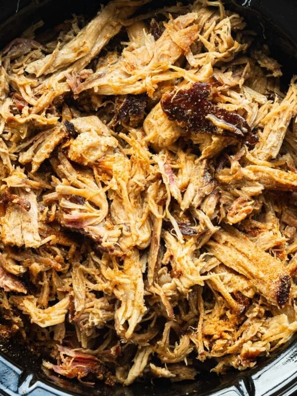 Tender slow cooker pulled pork shredded and piled in a slow cooker.