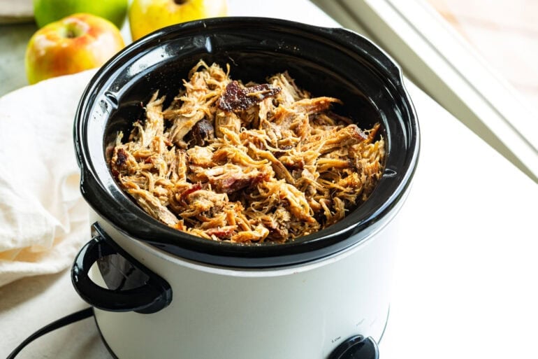 Tender pulled pork shredded in the slow cooker with cooking juices.