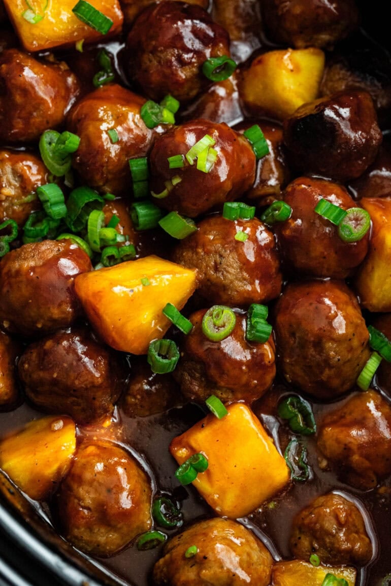 juicy saucy hawaiian meatballs mixed with chunks of pineapple and sprinkled with chopped green onions