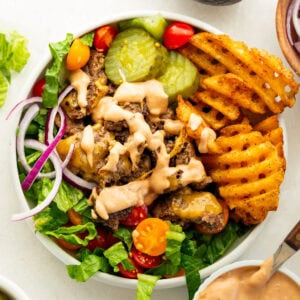 Smash burger bowl with crispy ground beef, waffle fries, romaine, tomatoes, cheese, pickles and burger sauce