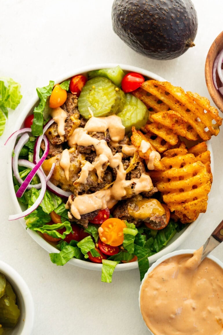 Smash burger bowl with crispy ground beef, waffle fries, romaine, tomatoes, cheese, pickles and burger sauce