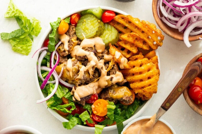 Loaded smash burger bowl with crispy ground beef, waffle fries, romaine lettuce, tomatoes, pickles, melted cheese and creamy burger sauce.