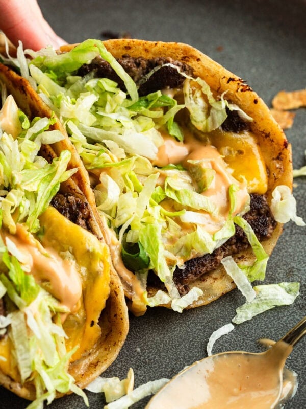 a hand picking up a smash burger taco