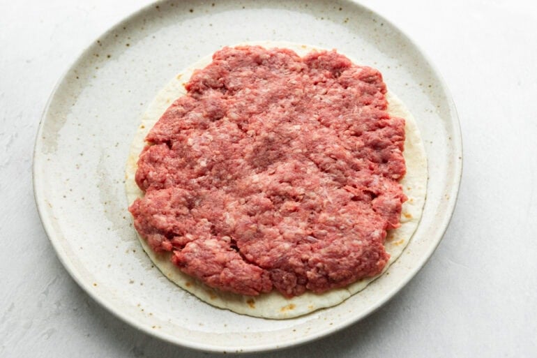 a flour tortilla stopped with a thin layer of ground beef