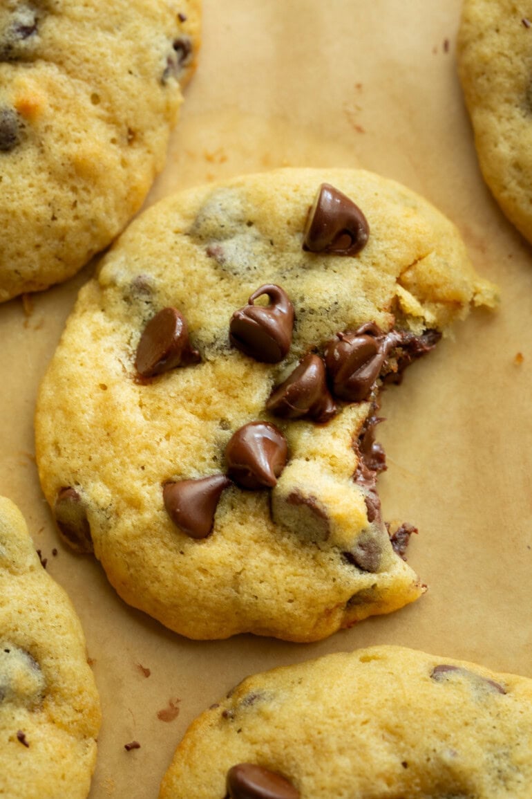 a banana chocolate chip cookie with a bite taken out of it topped with melty chocolate chips