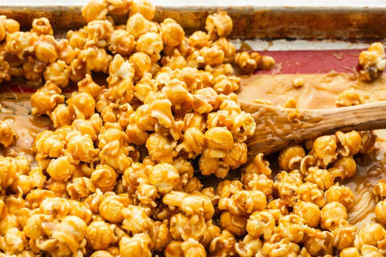 Soft caramel popcorn spread across a lined baking sheet to cool