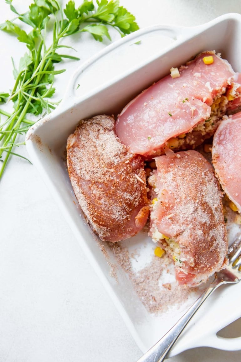 Four pork chops that have been stuffed and placed in a baking dish.