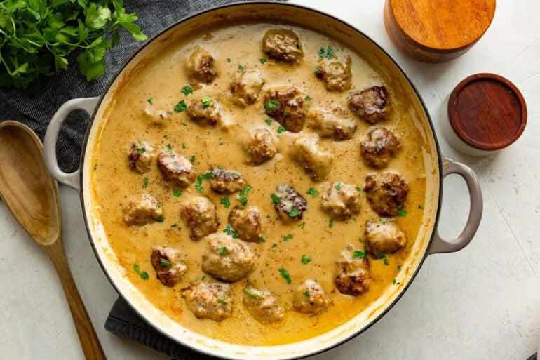 a large dutch oven full of golden brown Swedish meatballs sitting in a thick gravy sauce