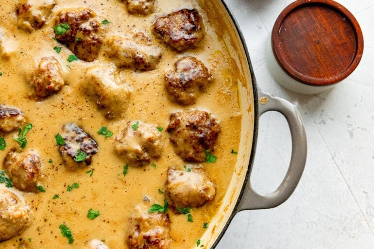 a large dutch oven full of Swedish meatballs simmering in a creamy gravy