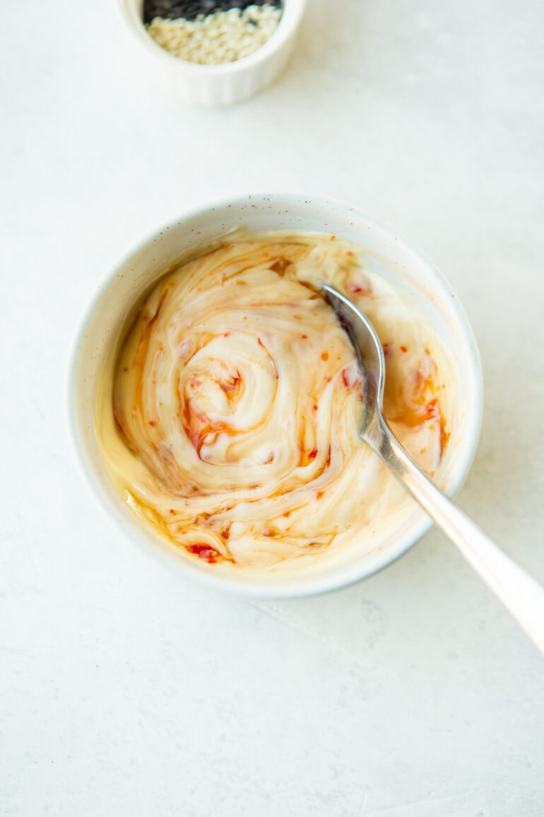 a photo of a small bowl of a creamy sauce with a spoon sticked into it. it is sweet chili mayo.