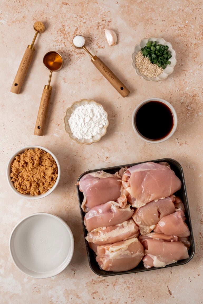 all the ingredients for teriyaki chicken including raw chicken thighs, brown sugar, soy sauce, minced garlic, cornstarch, etc.
