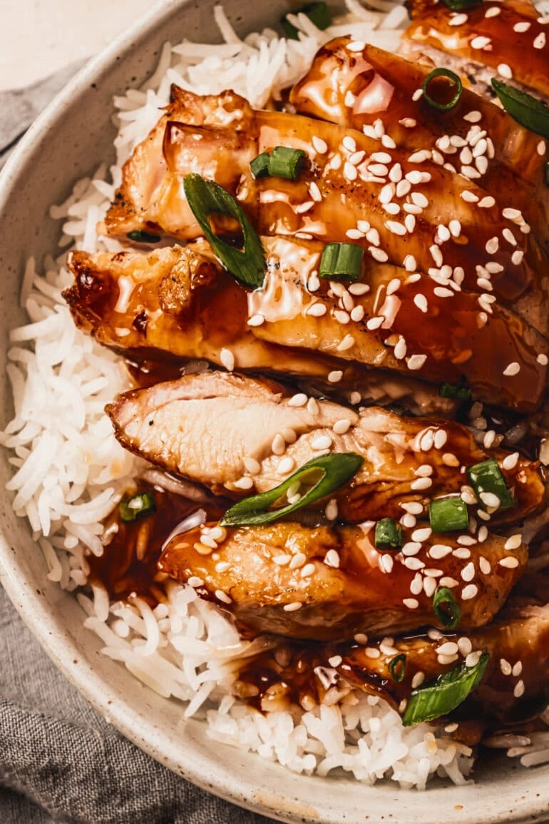slices of chicken thighs topped with teriyaki sauce and sprinkled with sesame seeds and green onions