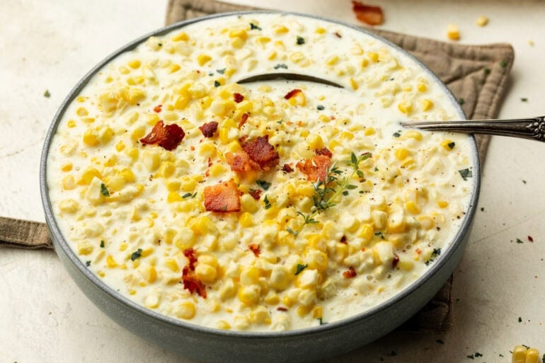 the best creamed corn I have ever had. Like, ever. I may have licked the the bowl. ohsweetbasil.com A bowl of smooth, creamy corn topped with crumbled bacon and bright green herbs.