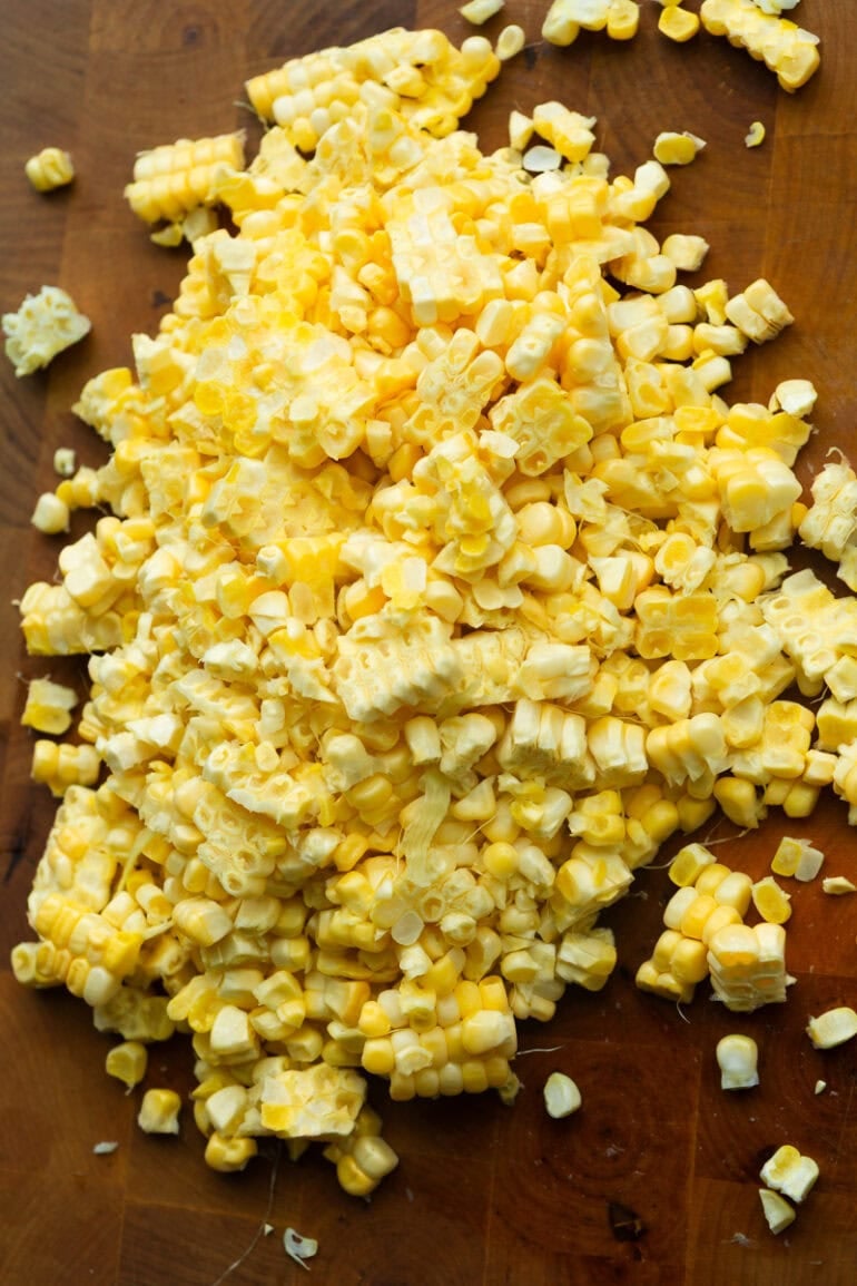 Fresh cut corn kernels on a wooden cutting board