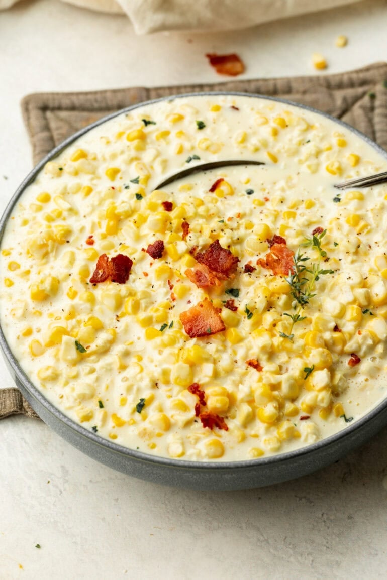 Golden, rich creamed corn in an large bowl, finished with bacon and fresh chopped herbs.