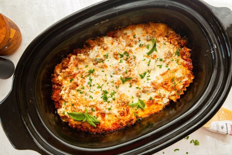 Finished slow cooker lasagna topped with melted mozzarella and fresh parsley