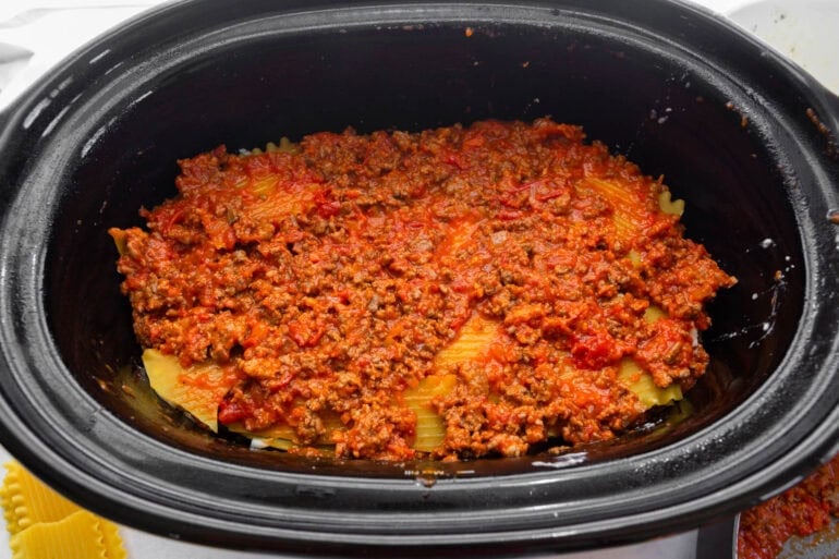 Marinara meat sauce spread over the bottom of a slow cooker