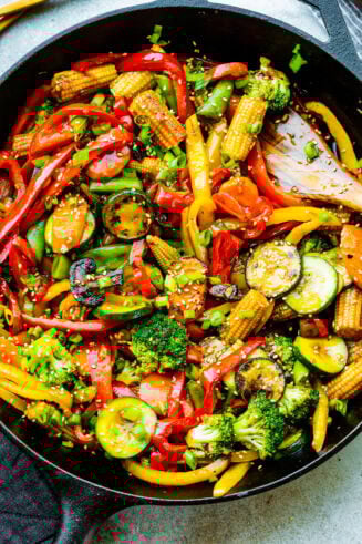 a photo of bright and colorful stir fry vegetables in a large cast iron skillet