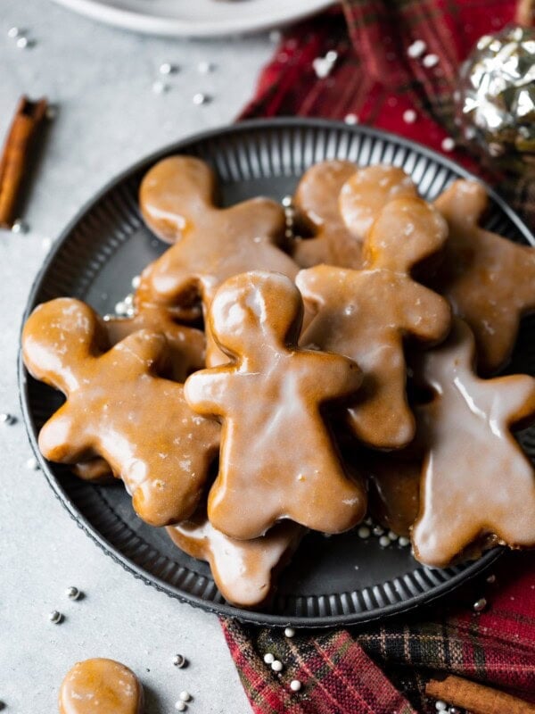 a photo of a plate full of thick and chewy gingerbread men cookies covered in a light glaze.