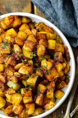 a photo of a large serving bowl filled with crispy fried potatoes topped with fresh herbs