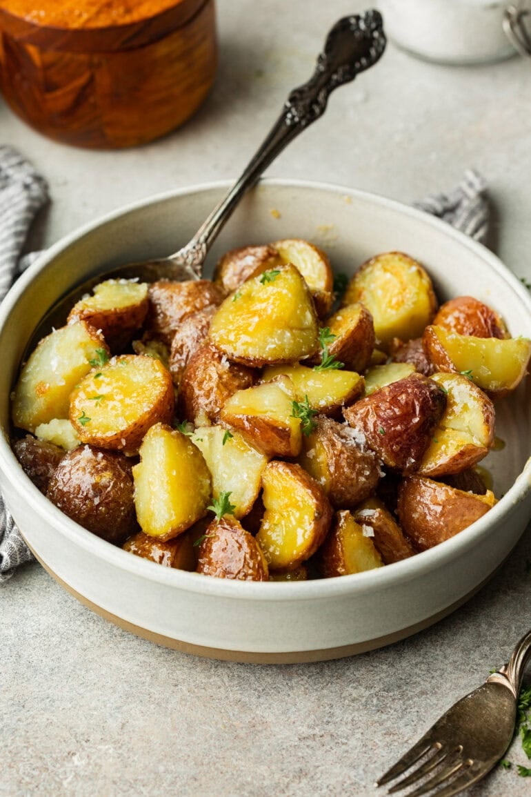 White bowl filled with golden red potatoes, their crispy skin and soft centers making them look irresistible.