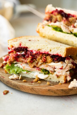 a photo of a half a turkey sandwich showing the cross section of the sandwich loaded with stuffing, cranberry sauce, turkey, lettuce, etc.