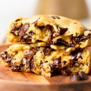 a thick chocolate chip cookie that has been broken in half and stacked on top of each other so you can see the inside of the gooey cookie