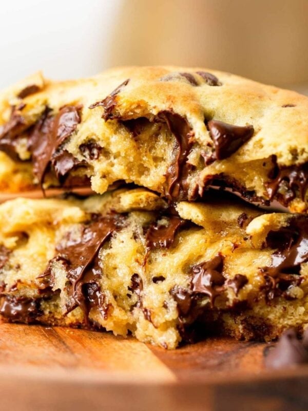 a thick chocolate chip cookie that has been broken in half and stacked on top of each other so you can see the inside of the gooey cookie