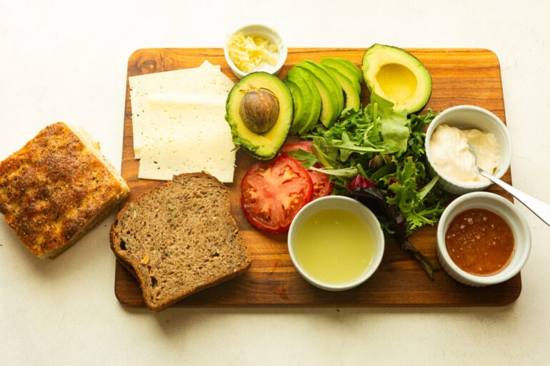 all the ingredients for a turkey bacon avocado sitting on a wooden cutting board
