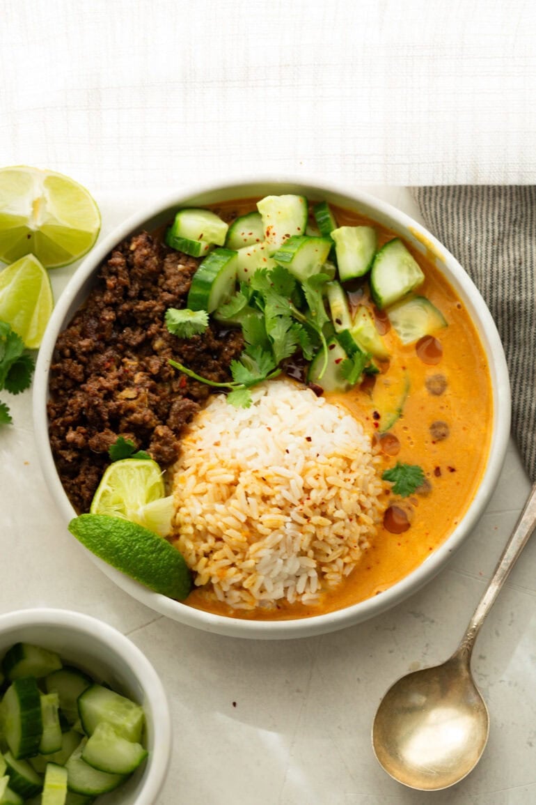 Viral coconut curry beef broth bowl with crispy ground beef, rice, cucumber, cilantro and lime